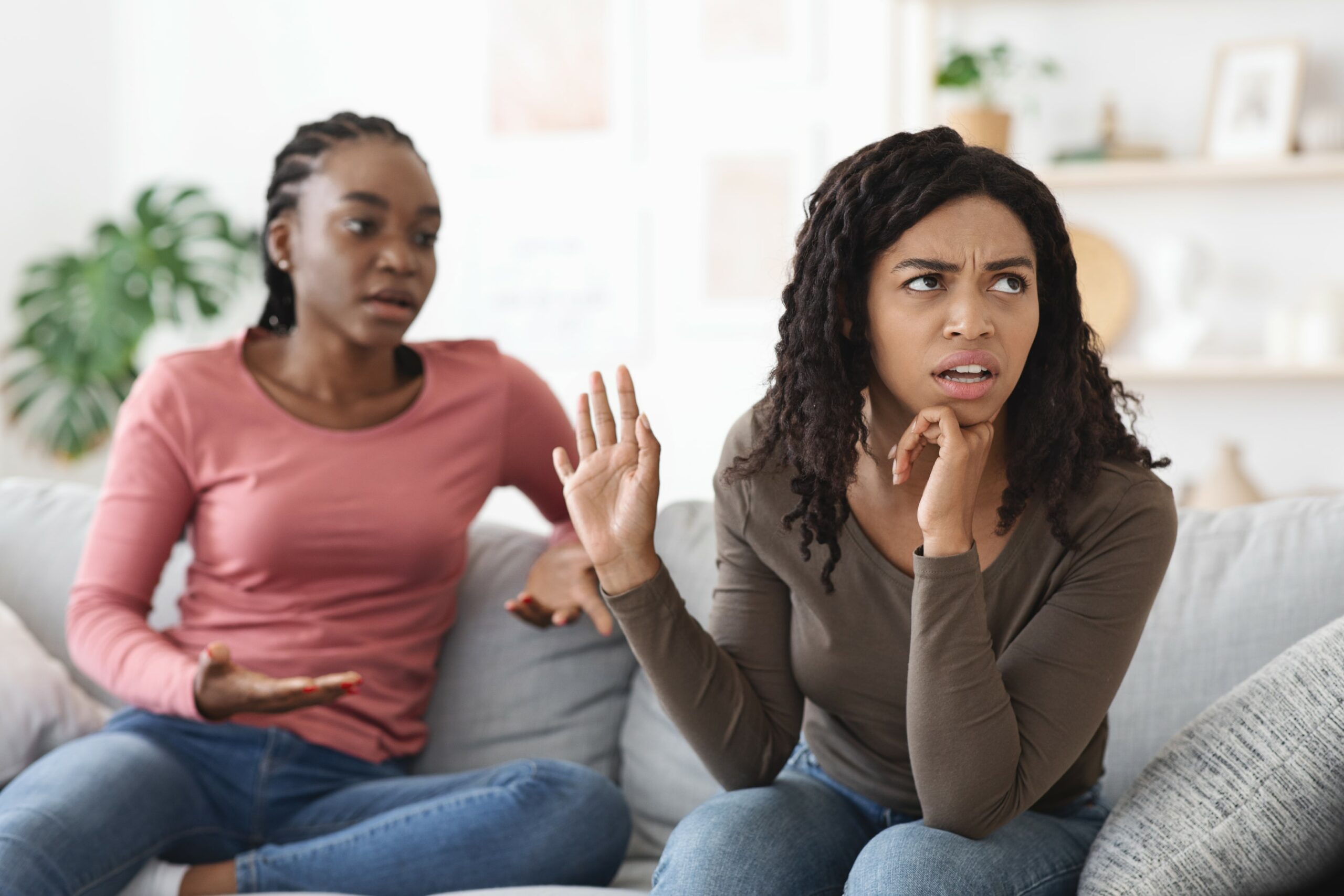 Image of lesbian couple in NYC on the sofa with one partner stonewalling the other partner in their conversation.